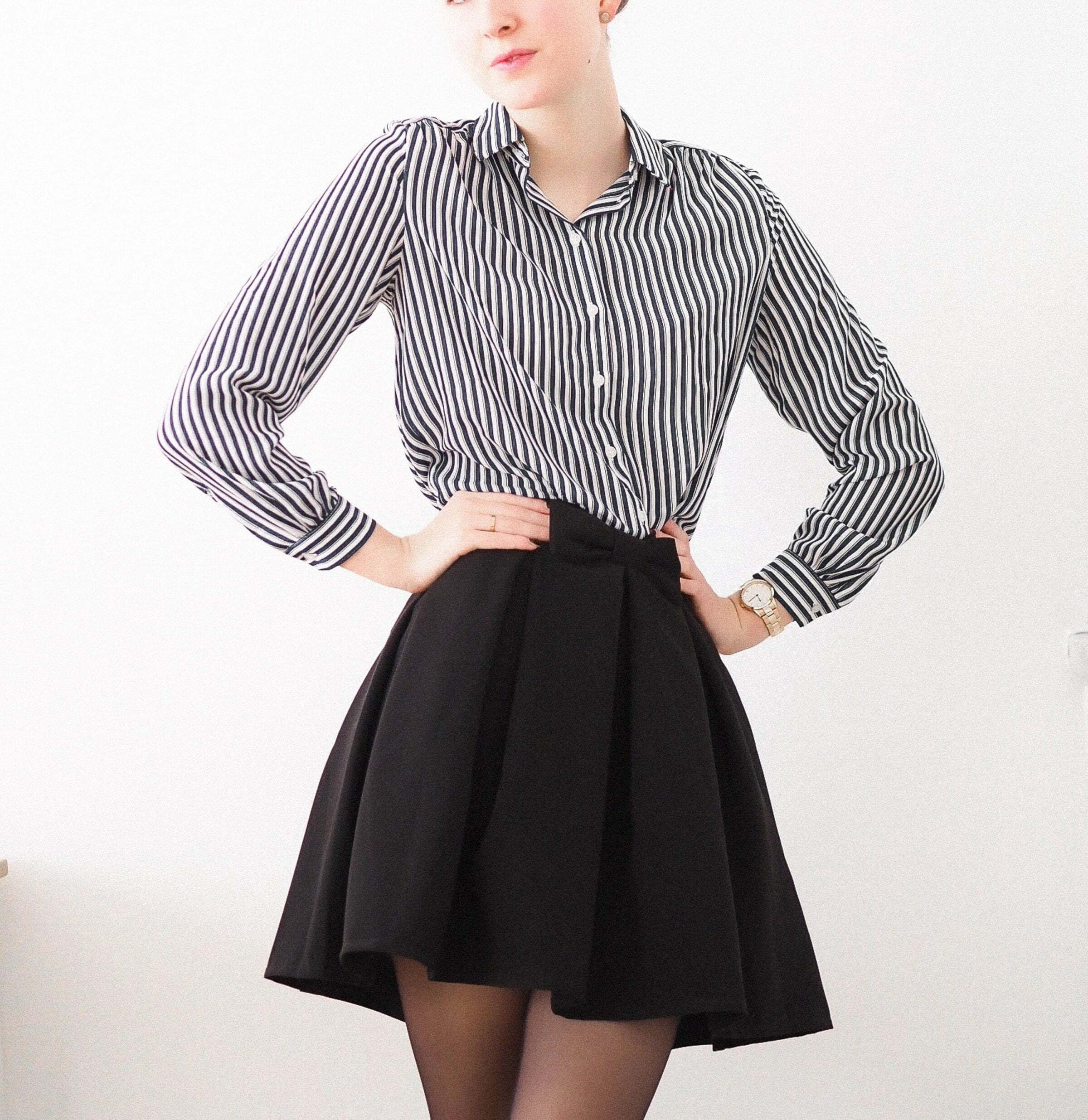 A woman stands with her hands at her sides, wearing a black skirt that appears to have been professionally tailored. She appears poised and confident, perhaps ready for a formal occasion or business meeting.