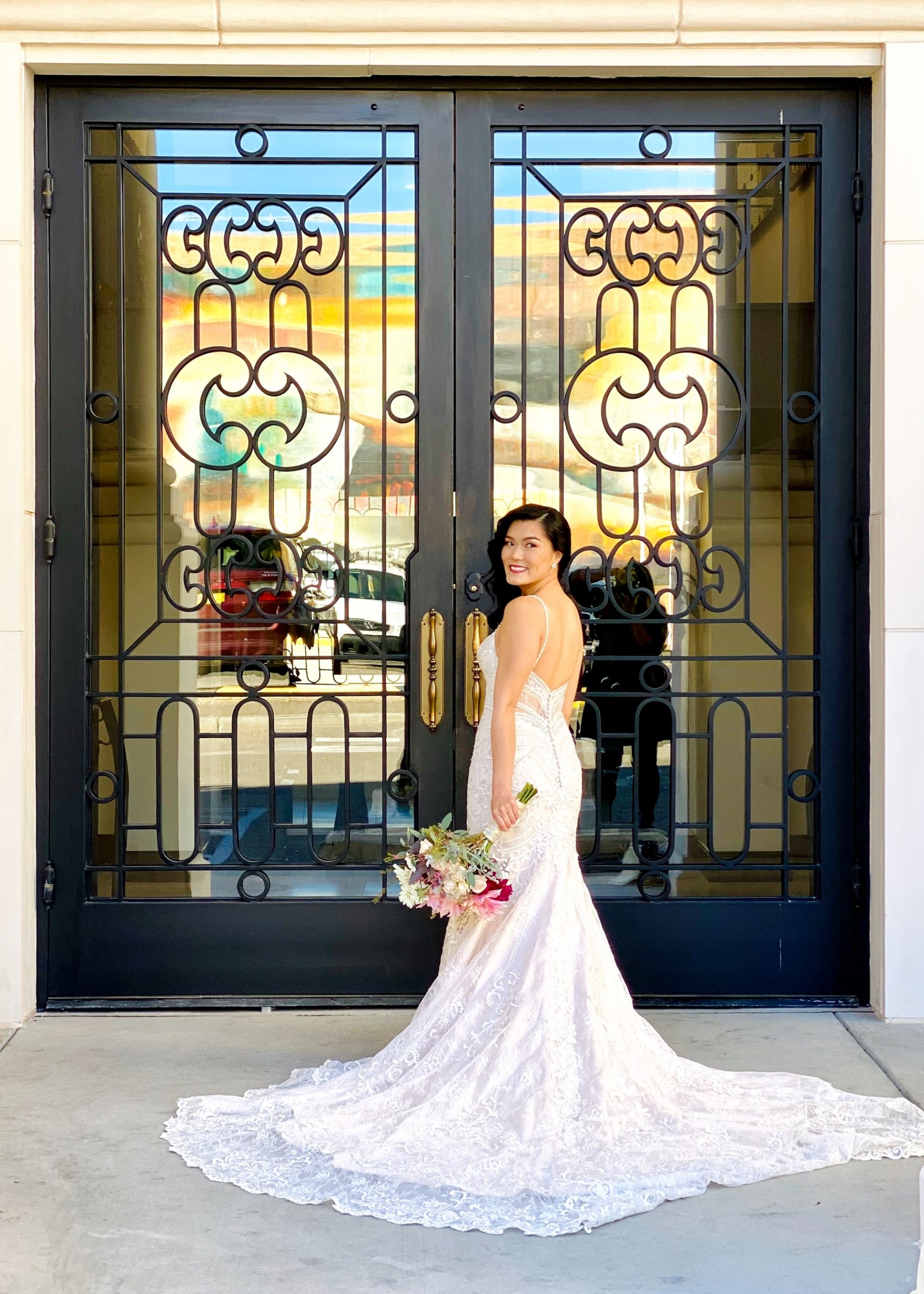 Smiling bride standing in front of glass colored door, looking back with joy.